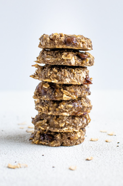 A stack of oatmeal chia cookies on a white background with some oats around them.