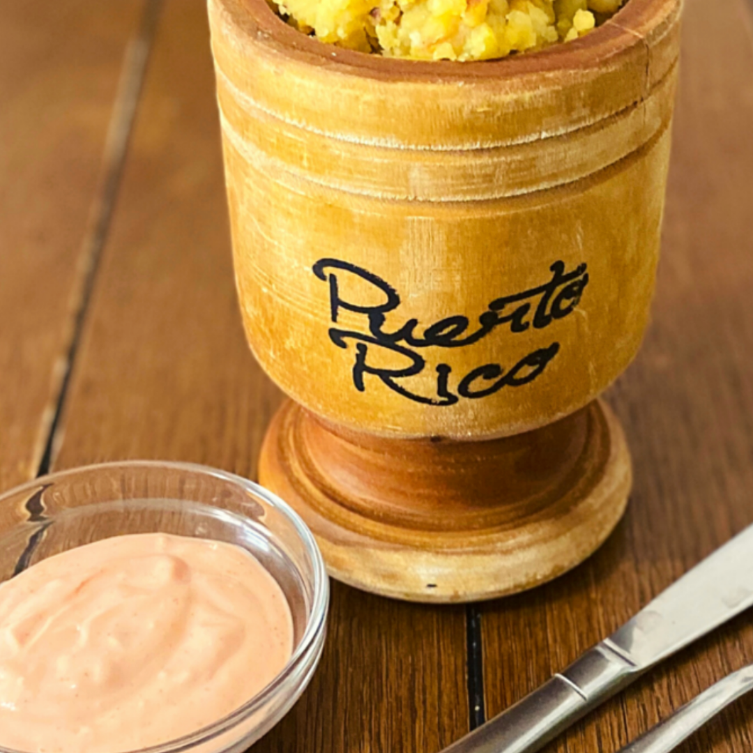 A wooden bowl of yellow mofongo (mashed plantains) that says 